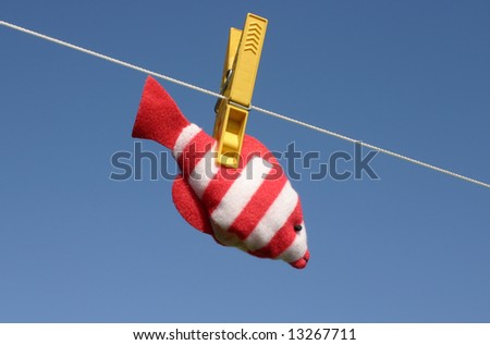 Colorful toy fish hanging on the laundry wire against blue sky