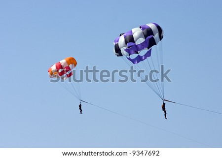 Parachute with soaring people on a background of the blue sky