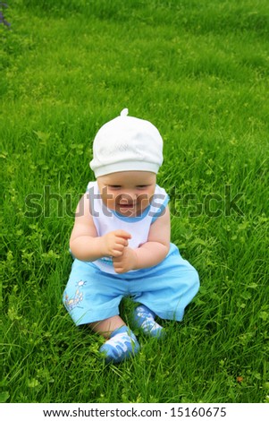 little boy with a happy kind sits on a grass