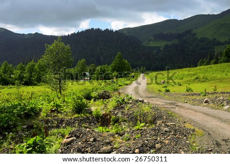country road away in mountains on a background cloudy sky