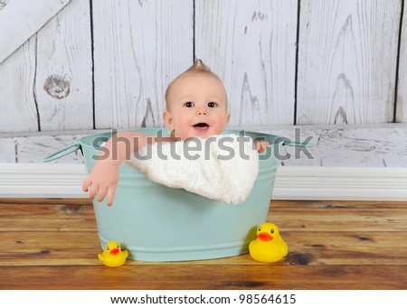 sweet baby boy playing peek-a-boo in washtub