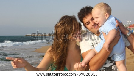 Young family with the small son on the bank of the Mediterranean sea