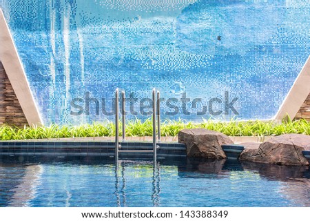 Blue swimming pool with steel ladder and brick wall