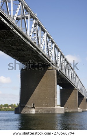 Bridge with bridge-walking bridge and small people in gray coveralls on top of the Old Little Belt Bridge.