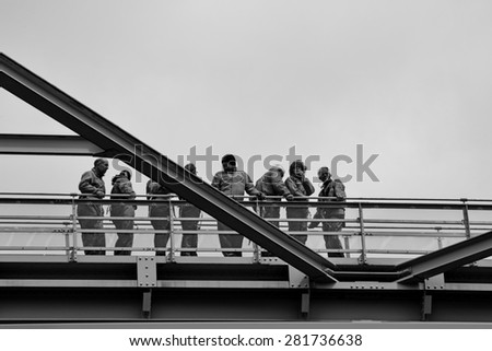 MIDDELFART, DENMARK - MAY 23, 2015: Bridge with bridge-walking bridge and a group of people in gray coveralls on guided tour on top of the Old Little Belt Bridge.