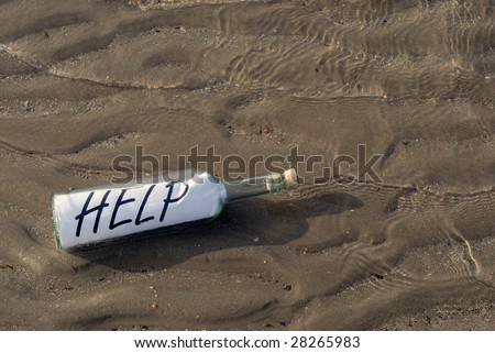 Message in the bottle washed ashore on the beach. Help written on paper in the bottle.