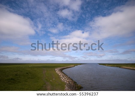 Ribe River outside the dike. The Wadden Sea National Park with sheeps. View from lock in Ribe dike.