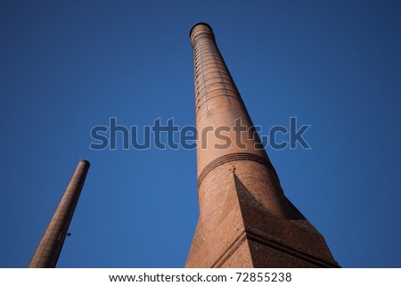 Two brick factory chimneys alone and sky blue