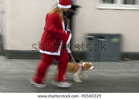 MIDDELFART - DECEMBER 11: Father Christmas Run in Middelfart, Denmark. Woman and dog running Christmas run in Denmark December 11, 2011 in Middelfart, Denmark.