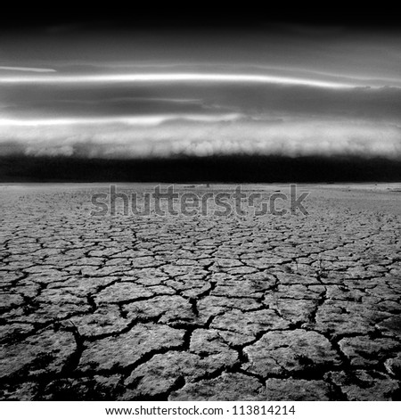 A severe storm approaching the drought cracked ground of a dry lake bed.
