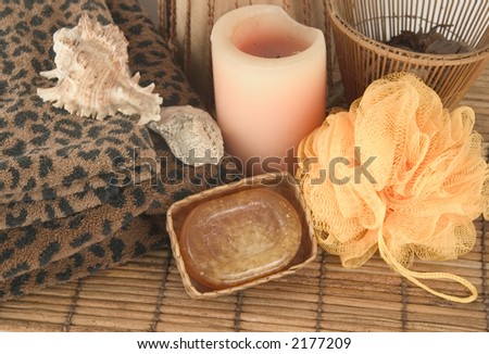 Soap, candle, sponge, sea shells and leopard towels on bamboo mat