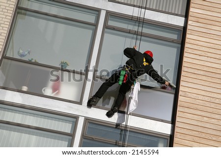 Climber on job as windows cleaner in a quiet new apartment building by the waterfront of Nyborg, Denmark.