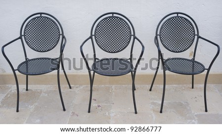 Four empty garden chairs in Italian patio on a hot day.