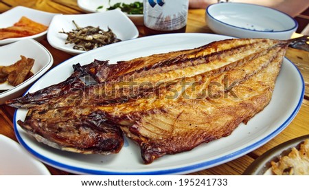 Korean style grilled fish on a table with snacks