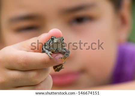 A young girl holds an American toad