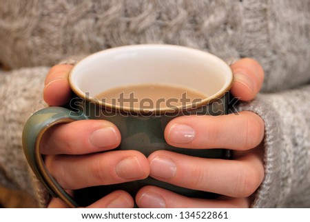 Two hands keeping warm, holding a hot cup of tea or coffee