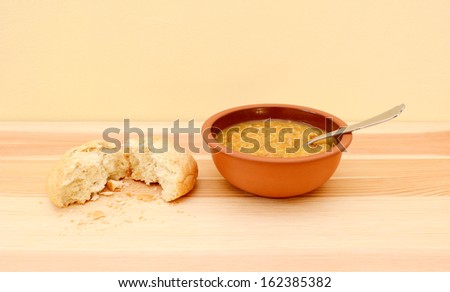 Bowl of delicious vegetable soup with a bread roll torn in half