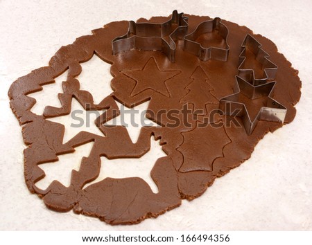 Gingerbread dough rolled out with cutout shapes and cookie cutters - star, reindeer, Christmas tree, holly leaf and bell