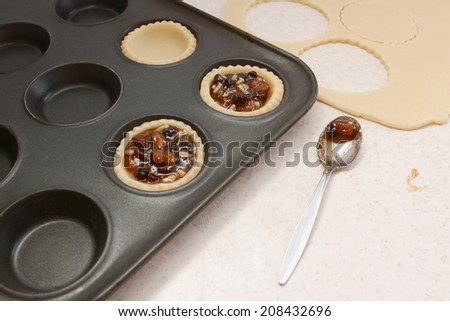 Filling pastry cases with mincemeat, with a used teaspoon on worktop