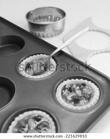 Using a teaspoon to fill pastry cases with festive mincemeat, dough and cutter beyond - monochrome processing