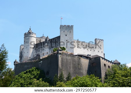 Hohensalzburg Fortress in Salzburg, Austria, with the Austrian flag flying against a blue summer sky