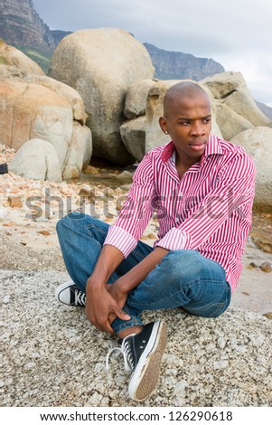 Young handsome african american man relaxing on the Cape Town beach located in South Africa