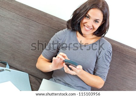 Young woman doing her account, using a calculator, with a laptop on her knees