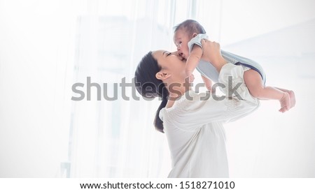 Portrait of asian mother lifting and playing with newborn baby, baby talking to mother. Health care family love together. Asian girl lifestyle. Asia mother's day concept 