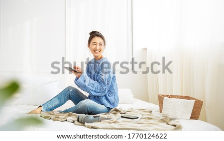 Asian woman with smile use tablet smartphone in blue winter sweater work home, Portrait beauty asia girl hygge relax in bedroom. Technology people connection digital online social media market banner