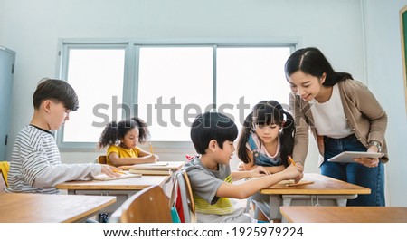 Pupil boy hi five with teacher in classroom at elementary school. Student boy studying in primary school. Children writing notes in classroom. Education knowledge, successful teamwork concept banner