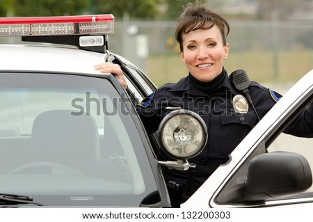 a female police officer smiling next to her police car.