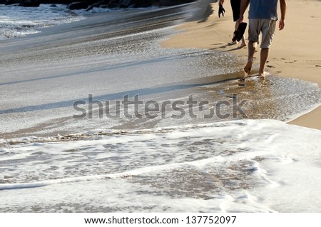 two people walking on the sand at D.T. Flemming Beach on the Island of Maui.
