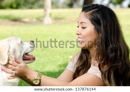 A smiling woman with her pet dog in the park.