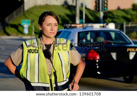 A female police officer staring and looking serious during a traffic control shift.