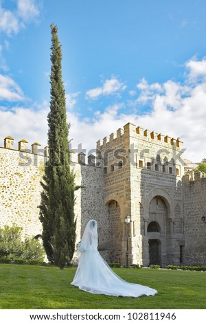 The bride in a dress with a loop is photographed at walls of ancient city Toledo in Spain