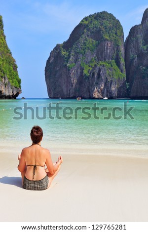 Trim elderly woman hatha yoga on the beach. Maya Bay Island in the Andaman Sea, Thailand