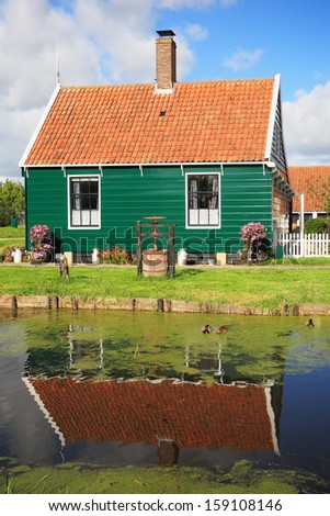 An ancient Dutch village. Cute little house with a red roof reflected in the river