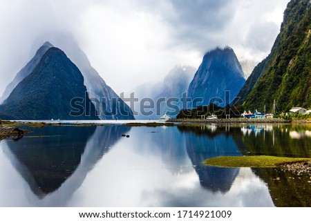 Land of hobbits - New Zealand. Port of tourist and pleasure ships, yachts and boats. Storm clouds cover the sky over the ocean fjord Milford Sound.  Concept of exotic, photographic tourism