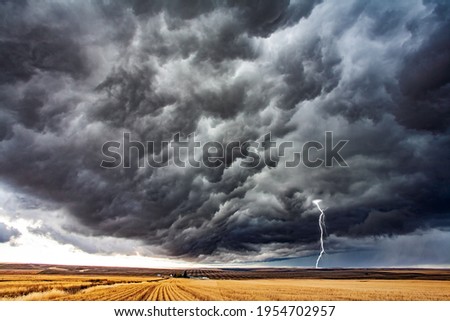 Storm in the steppe. Field after harvest. Heavy swirling storm clouds over a huge farm field. Late autumn in America 