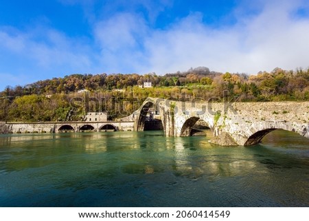 Italy, Lucca. The emerald cold water of the river reflects the ancient asymmetrical arches of the bridge. The bridge of Mary Magdalene crosses the Serchio River.  Stock fotó © 