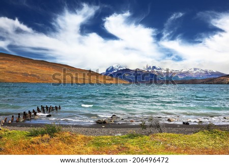 The storm on the lake. The mountains surrounding the lake, almost hidden flying clouds.  Boat dock poured foaming waves