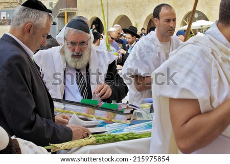 JERUSALEM, ISRAEL - SEPTEMBER 20, 2013:  Prayer at the Kotel. Religious Jews in white prayer shawls are going to pray at the Western Wall of the Temple. Sunny morning in the holiday of Sukkot