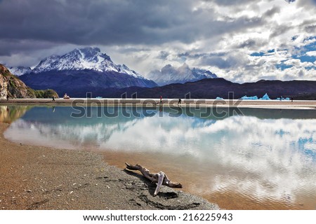 After the storm. Gray lake in the national park Torres del Paine in Chilean Patagonia. Clouds are reflected in ice water of the lake. The blue iceberg is in the distance visible