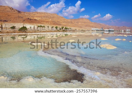 Israeli coast of the Dead Sea. The path from salt picturesquely curls in salty water. Hotels are reflected in the sea ashore