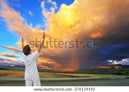 Giant cloud illuminated by the sunset. Yoga on the road. Elderly woman in white performs asana \