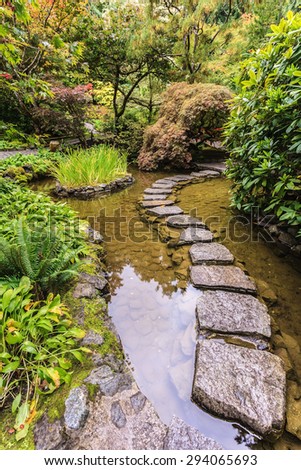 The track of stones in  water in Japanese part of garden. Decorative private garden on Vancouver Island in Canada