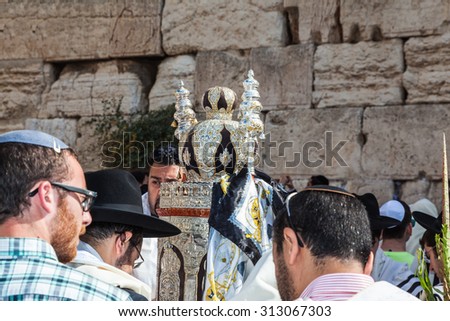 JERUSALEM, ISRAEL - OCTOBER 12, 2014: Morning autumn Sukkot. The area in front of Western Wall of  Temple. Crowd of Jewish worshipers in white wearing prayer shawls. On table there is Torah Roll.