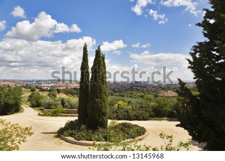 Rural hotel, twisting narrow road and cypresses in vicinities of ancient city Toledo in Spain