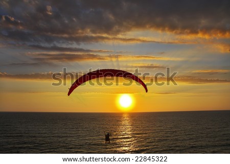 Flight on an operated parachute in twilight on a sunset. A magnificent parachute in the cloudy sky above the sea