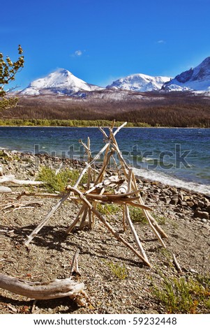 Ritual American Indian construction from white wooden bough on coast of cold mountain lake